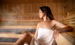 Beautiful woman in white towel relaxing in sauna