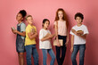© Prostock-studio - Multinational schoolkids with textbooks looking at camera over pink background, portrait