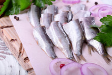Salted Sprats Served On Piece Of Parchment With Parsley And Red Onion