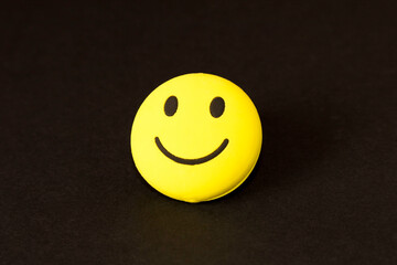 Wall Mural - Yellow smiley face on dark background. The concept of a positive mood.