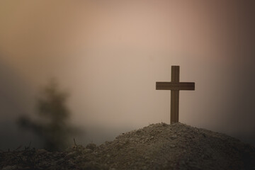 A wooden cross on a mound The background of the setting sun is about to set. Christian religious concepts, crucifixion of faith and faith in God.