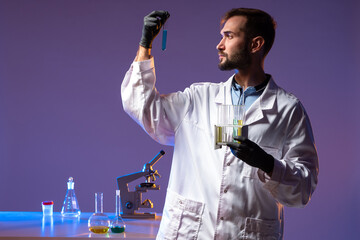 Poster - the scientist stands and holds test tubes with colored chemical liquids. a chemist in a white coat a