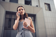 Woman With Notepad Speaking On Mobile Phone