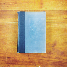 An Old Blue Book Lying Flat On A Wooden Table.
