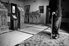 Lower portion of old man walking with cane at Greek church