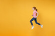 © ViDi Studio - Full length children studio portrait side view of smiling little ginger redhead kid girl 12-13 years old wearing pink casual t-shirt posing jumping like running isolated on yellow color background.