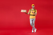 © ViDi Studio - Full length step delivery employee man in yellow cap t-shirt thermal food bag backpack hold pizza in cardboard flatbox work courier service during quarantine covid-19 virus isolated on red background.