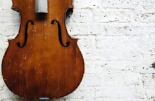 Old Weathered Cello Against A Textured White Wall