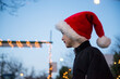 © Cara Dolan/Stocksy - Happy boy wearing Santa hat at Christmas tree stand