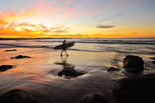 Blurred Surfer Heading Into The Ocean At Sunset
