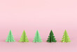 Christmas composition with paper trees on a pink background. Christmas origami fir trees with copy space for text. New Year's minimal concept.