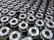 batch of shiny round steel parts background, close-up with selective focus and blur