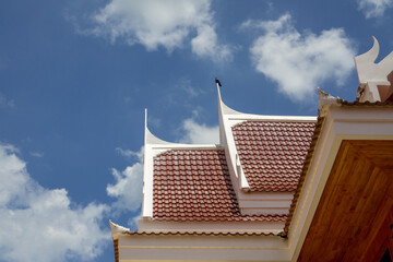 Wall Mural - The roof of a building in a Thai temple with birds perched and blue sky.