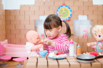 young girl pretend play babysitting with baby doll at home