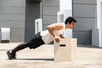 Handsome Indian sports man doing push up exercise outdoors on building rooftop, home workout in the open air concept