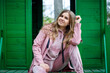 © DSMT - Stylish young girl with blond hair of European appearance sits on the steps, dressed in a pink suit, modern womens fashion, casual clothes