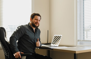 Wall Mural - Male broker sitting at cabinet with pen and laptop.