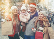 © JackF - Portrait of cheerful man and woman and their happy daughters posing with paper bags near counters at Christmas fair
