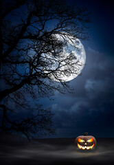 Wall Mural - one spooky halloween pumpkin, jack o lantern, with evil face and eyes under the silhouette of a tree