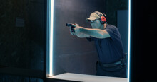 Mature Shooter Firing Pistol In Dark Range