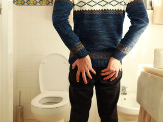 Selective focus of Man holding his bottom in pain,which In the bathroom, his home is unhappy with constipation, diarrhea, food poisoning, health and medical concepts.