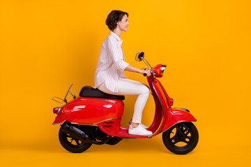 Wall Mural - Side profile full length photo of pretty young lady riding motorcycle enjoying trip mountains wind hair mountains wear white striped shirt isolated yellow bright color background