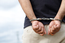 Arrest The Offender. Prison Male Criminal Standing In Handcuffs With Hands Behind Back. 