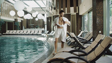 Handsome Man Taking Off Clothes Near Water Pool At Luxury Hotel.