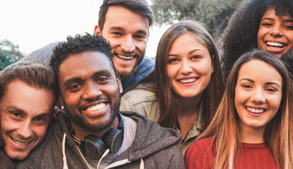 happy millennial friends from diverse cultures and races having fun in front of smartphone camera - 