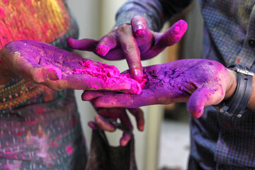 closeup photo of 3 hands with holi colors mixing the colors with finger. Holi festival concept image