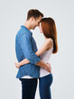 Profile side of smiling happy couple. Portrait image of standing close and looking at each other models in love studio concept, isolated over bright grey background. Man and woman posing.