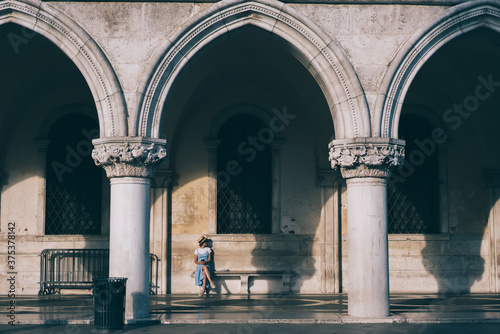 Carefree woman sitting on bench of gallery with columns