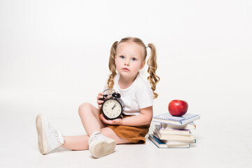 Wall Mural - Education and school concept. Smiling little student girl with book clock and apple lying on the floor