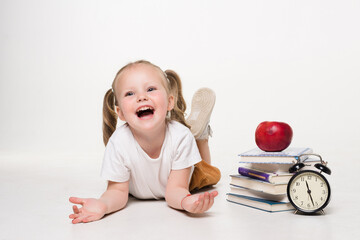 Wall Mural - Education and school concept. Smiling little student girl with book clock and apple lying on the floor