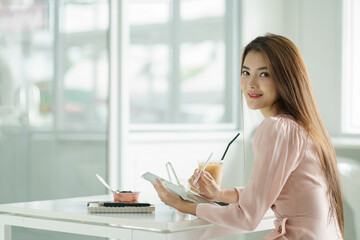 Fototapete - Young businesswoman writing her assignment on a mockup tablet in the office room.
