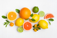 Citrus Fruits And Green Leaves On White Table Top View