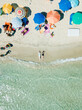 PUGLIA, ITALY - SEPTEMBER 06, 2018: Aerial view two young girls in swimwear lie on sand beach Punta Prosciutto Italian Maldives. Summer vacation. People sun bathe swim relax under umbrellas. Sea waves
