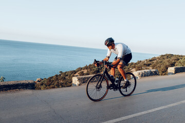 Wall Mural - Man cyclist pedaling on a road bike outdoors in sun set