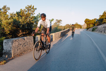 Wall Mural - Two professional male cyclists riding their racing bicycles in the morning together