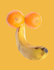 A flat lay of ripe banana and two fresh mandarine fruit represent a penis concept. isolated on white background. male genitals