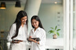 © Prathankarnpap - Office women are using a computer tablet while standing together in a comfortable office.