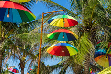 Street Lamps Decorated With Colorful Umbrellas Hang On A Pillar In Street Against The Blue Sky And Coconut Palm Tree On A Sunny Day