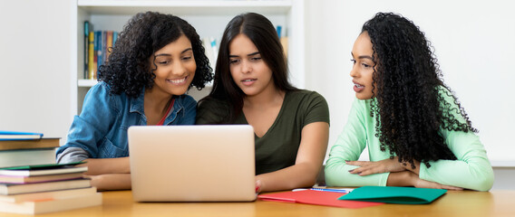 Group of latin american and indian students learning at computer