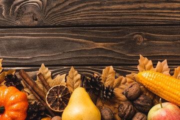 Wall Mural - top view of autumnal harvest and foliage on brown wooden background
