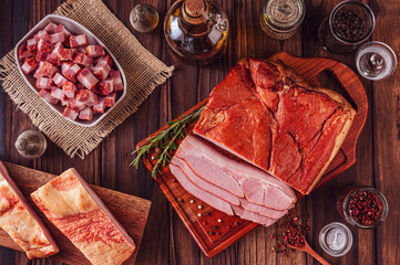 Fresh sliced bacon with rosemary branch and spices on the wood background - Top view