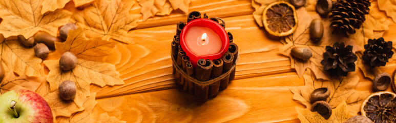 Poster - burning candle with autumnal decoration on wooden background, panoramic shot