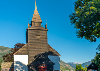 Leikanger Church, Leikanger village, on the northern coast of the Sognefjorden. Sogndal, Vestland. Norway. Built in 1250. White, stone  with a a large wooden steeple.