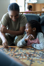 Laughing Mother And Daughter Assembling Jigsaw Puzzle In Living Room