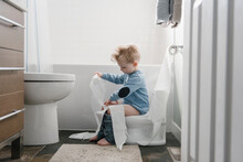 Boy Sitting On Toilet Holding Toilet Roll
