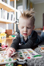 Young Boy Playing With Alphabet Puzzle On Floor At Home